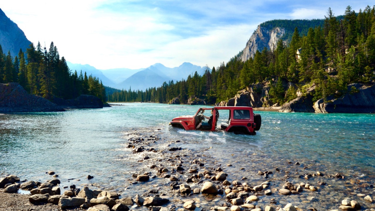 vue d'un Jeep Wrangler 2025 qui traverser une rivière dans une forêt
