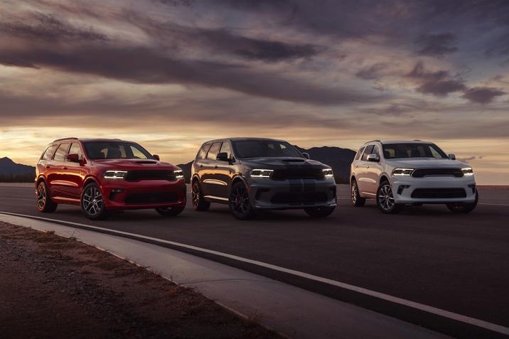 trois Dodge Durango 2021 côte-à-côte sur piste de course, phares avant allumés, ciel sombrant au couché du soleil