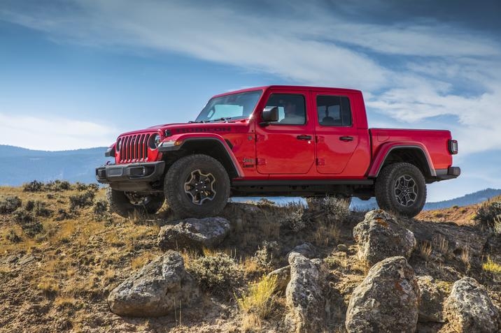 Jeep Gladiator Rubicon Ecodiesel 2021 garé sur une colline avec des rochers autour, ciel clair et partiellement nuageux